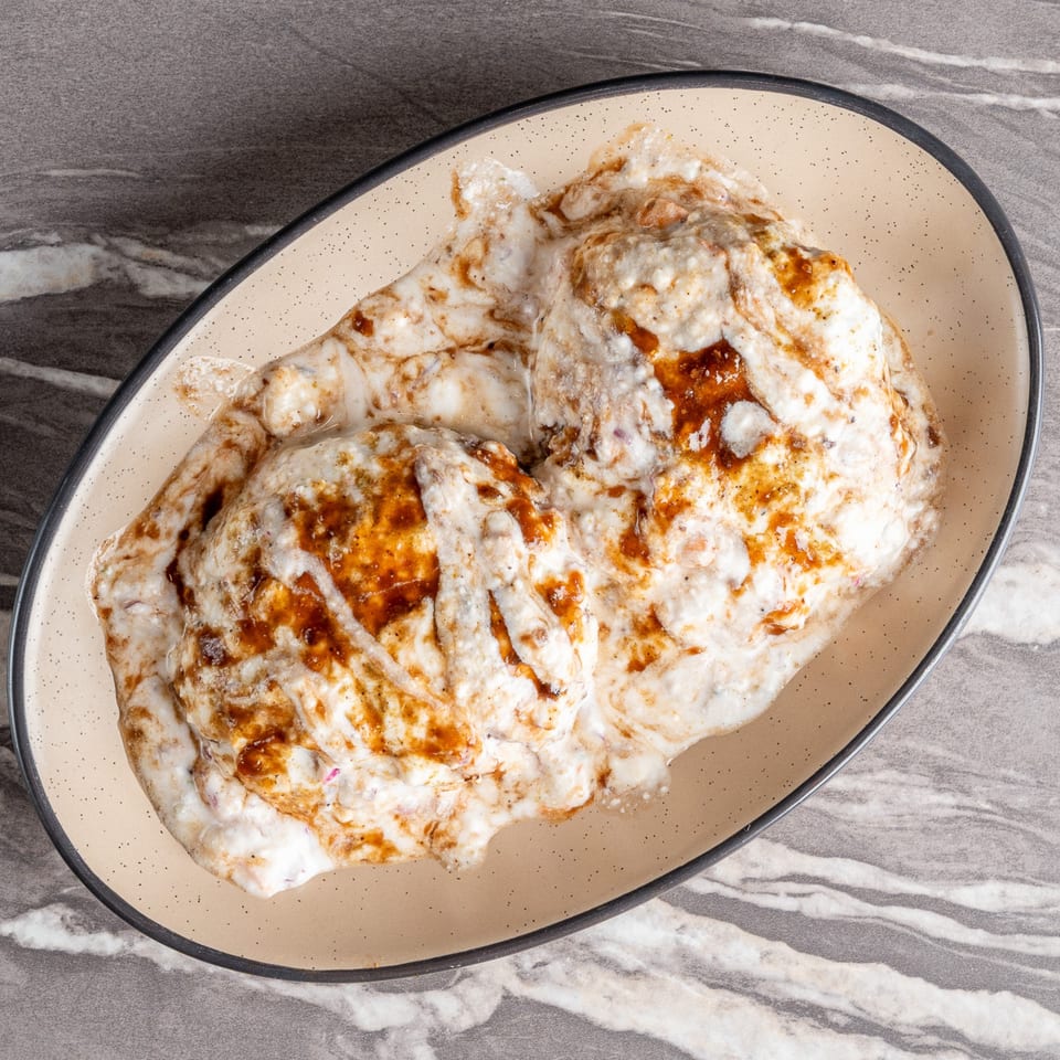 Dahi Bhalla, a popular Indian street food, served on an oval plate with yogurt and tamarind chutney.
